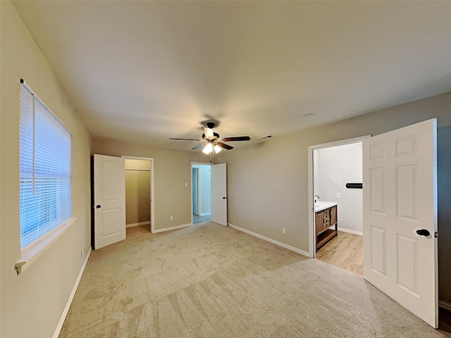 unfurnished bedroom with light colored carpet, ensuite bath, and ceiling fan