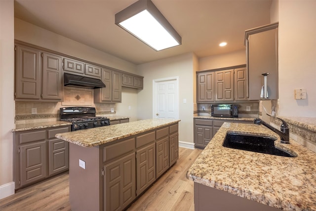 kitchen featuring sink, light wood-type flooring, black appliances, and a center island