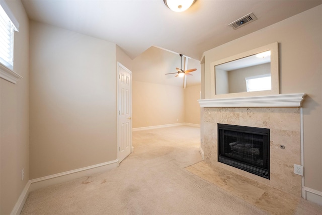 unfurnished living room with a fireplace, ceiling fan, a wealth of natural light, and light colored carpet