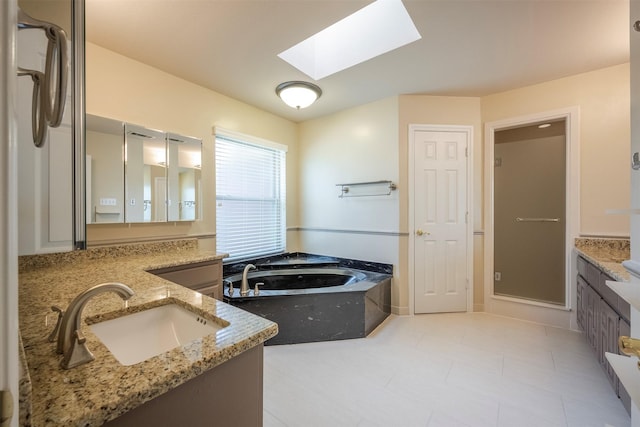 bathroom featuring a skylight, a bath, and vanity