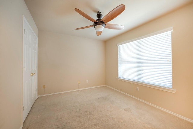 carpeted spare room featuring ceiling fan and a wealth of natural light