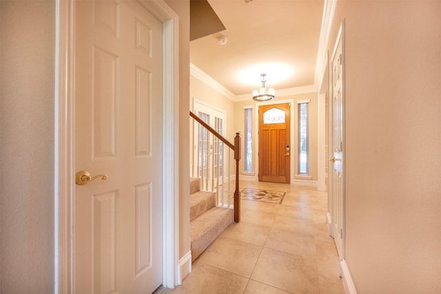 tiled foyer featuring crown molding and a chandelier