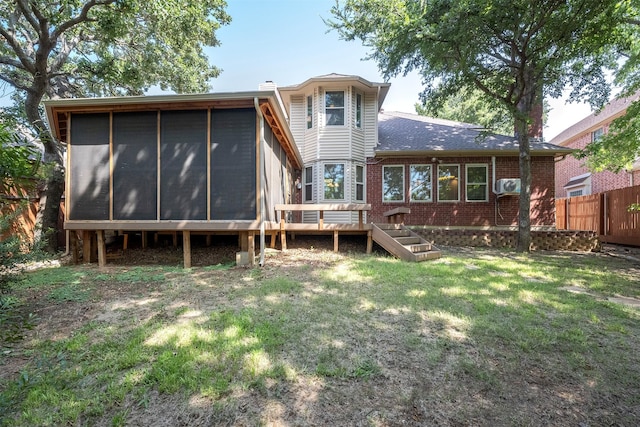 rear view of house featuring a deck, a sunroom, and a lawn