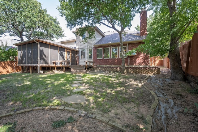 rear view of house with a yard, a sunroom, and a wooden deck