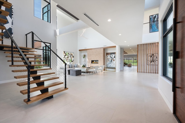 foyer entrance featuring a tiled fireplace and a high ceiling