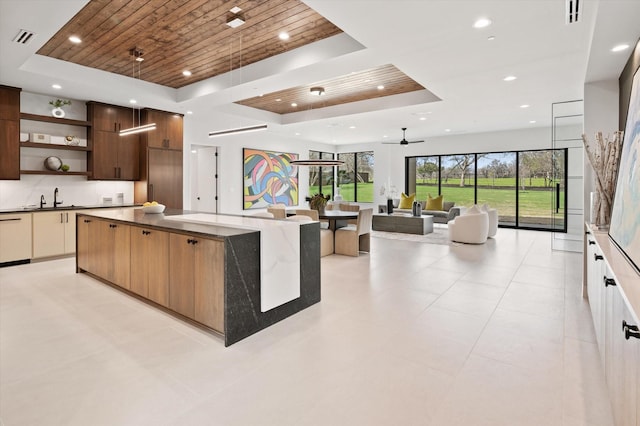 kitchen featuring ceiling fan, white cabinetry, a raised ceiling, and a large island