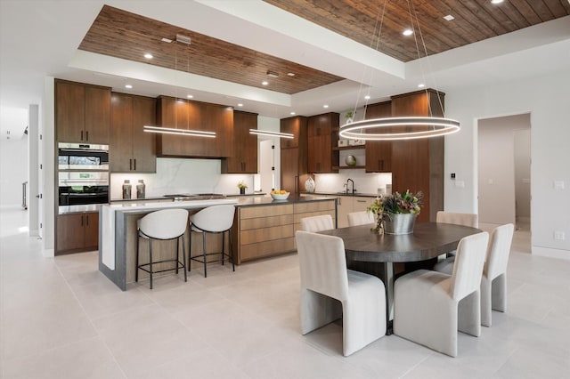 tiled dining space with wood ceiling, a tray ceiling, and sink