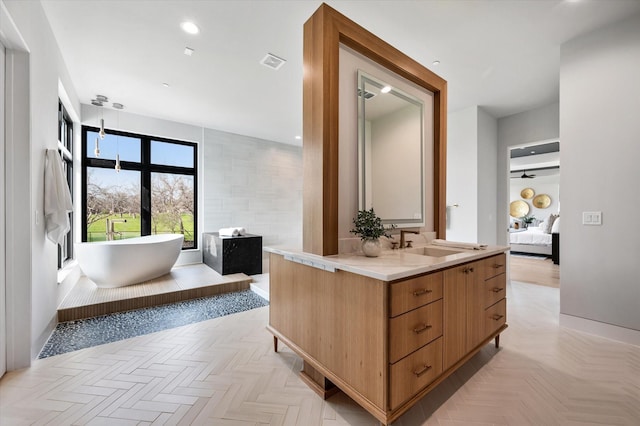 bathroom with a bath, vanity, and parquet flooring