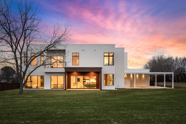 back house at dusk with a yard and a patio