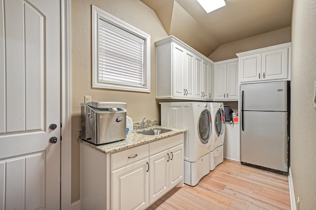 laundry room featuring cabinets, separate washer and dryer, sink, and light hardwood / wood-style flooring