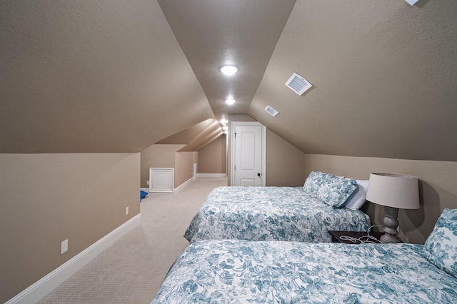 bedroom with light carpet, vaulted ceiling, and a textured ceiling