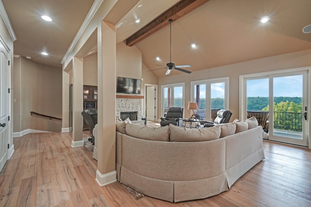 living room with beam ceiling, high vaulted ceiling, a stone fireplace, and light hardwood / wood-style floors