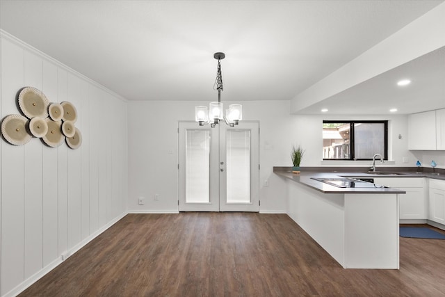 kitchen with decorative light fixtures, dark hardwood / wood-style floors, kitchen peninsula, sink, and white cabinetry