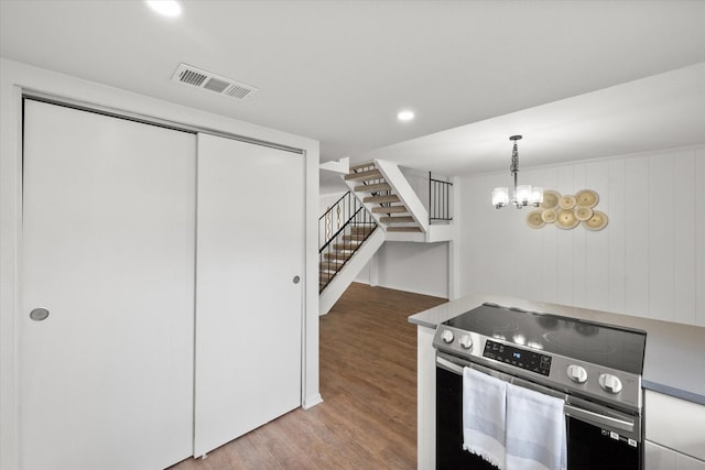 kitchen with a notable chandelier, pendant lighting, hardwood / wood-style floors, and electric stove