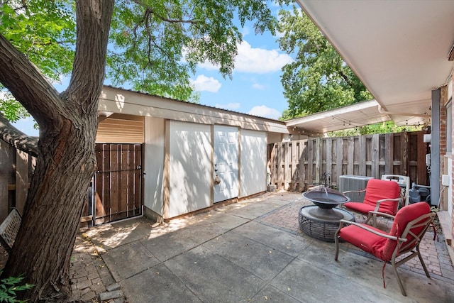 view of patio featuring central AC unit, an outbuilding, and an outdoor fire pit