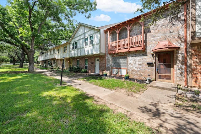 view of front of home featuring a balcony and a front yard