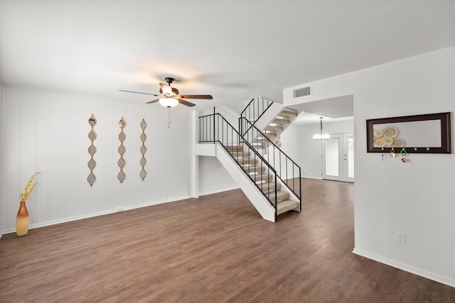 empty room with dark wood-type flooring and ceiling fan with notable chandelier