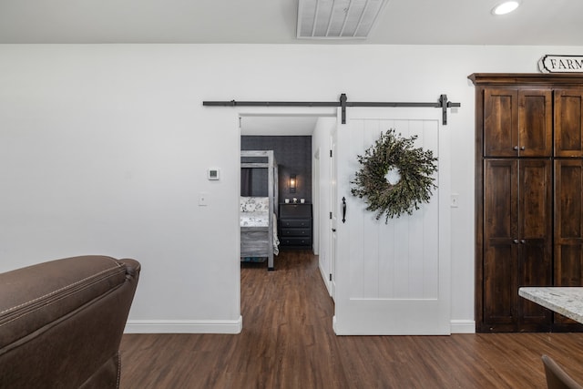 hall with a barn door and dark hardwood / wood-style flooring