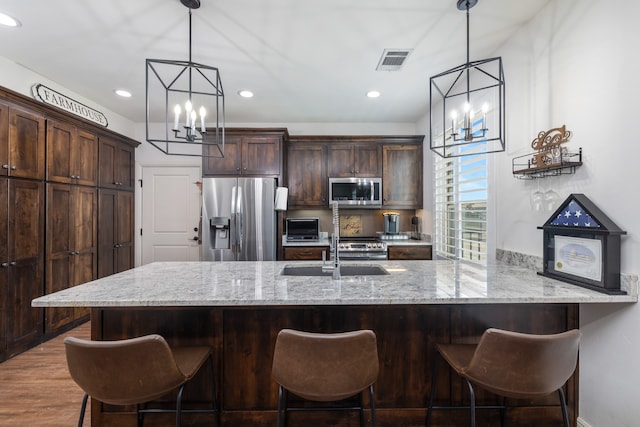 kitchen featuring appliances with stainless steel finishes, dark brown cabinetry, dark hardwood / wood-style floors, and hanging light fixtures