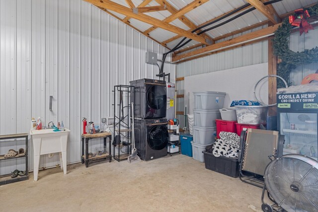 garage featuring sink, stacked washer and clothes dryer, and water heater