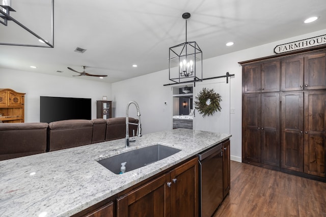 kitchen with ceiling fan with notable chandelier, sink, stainless steel dishwasher, dark hardwood / wood-style floors, and light stone countertops