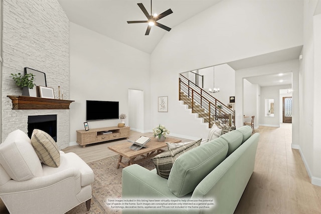 living room featuring a fireplace, ceiling fan with notable chandelier, high vaulted ceiling, and light wood-type flooring