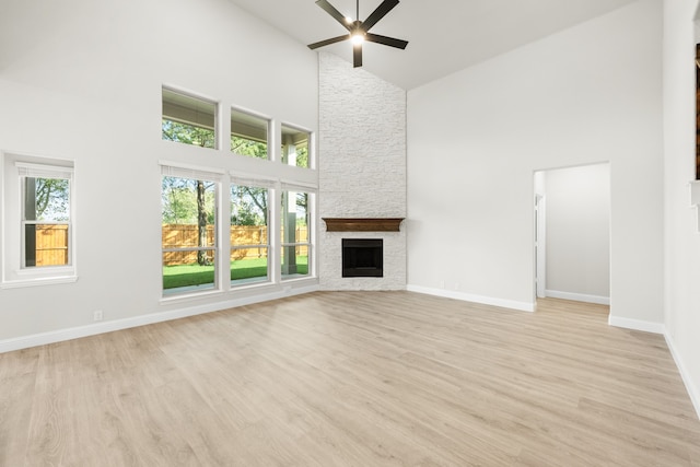 unfurnished living room featuring a fireplace, light wood-type flooring, and high vaulted ceiling