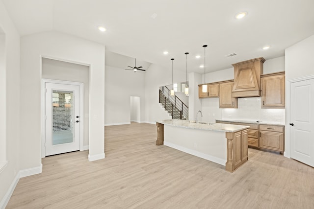 kitchen featuring a center island with sink, vaulted ceiling, sink, and light hardwood / wood-style floors