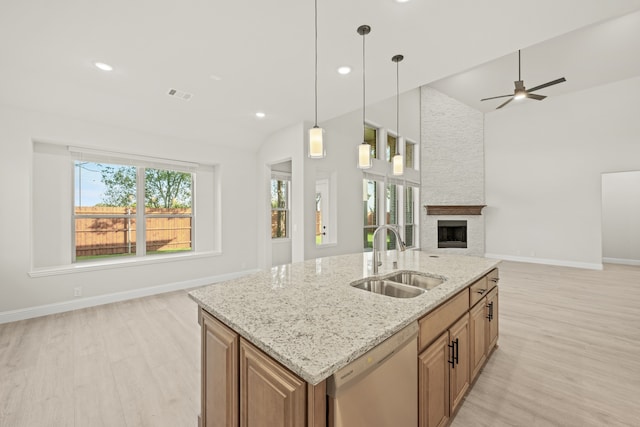 kitchen with sink, pendant lighting, light hardwood / wood-style floors, stainless steel dishwasher, and light stone counters