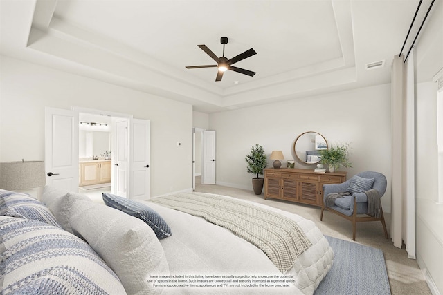 carpeted bedroom featuring connected bathroom, ceiling fan, and a tray ceiling