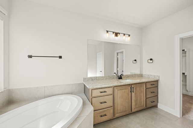 bathroom with tile patterned floors, vanity, and a relaxing tiled tub