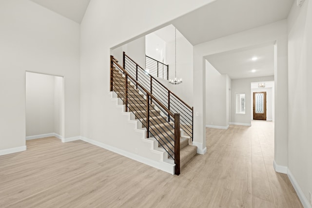 staircase featuring wood-type flooring and a notable chandelier