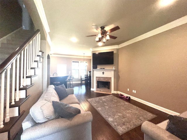 living room featuring a tile fireplace, ornamental molding, dark hardwood / wood-style floors, and ceiling fan