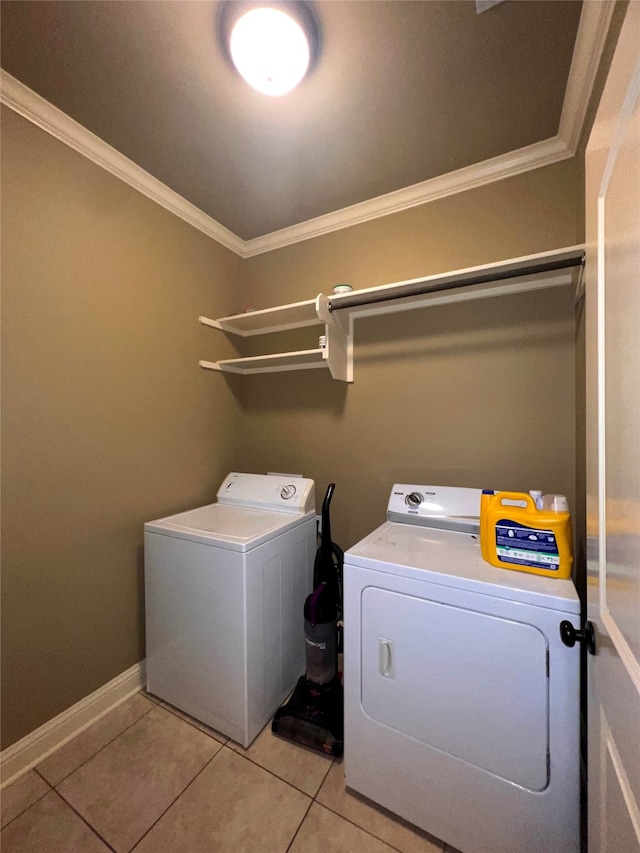 washroom featuring washing machine and dryer, ornamental molding, and light tile patterned floors