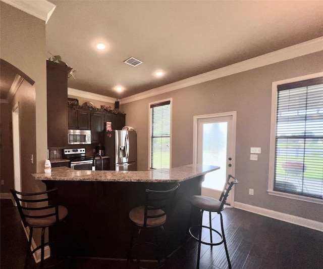 kitchen featuring dark wood-type flooring, appliances with stainless steel finishes, and crown molding