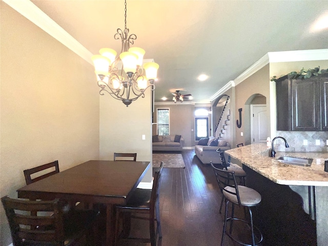 dining room with ornamental molding, dark hardwood / wood-style floors, sink, and a notable chandelier