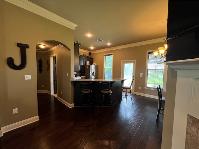 kitchen featuring dark wood-type flooring, stainless steel fridge, a kitchen breakfast bar, and kitchen peninsula