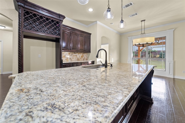 kitchen with sink, decorative backsplash, a center island with sink, and dark wood-type flooring