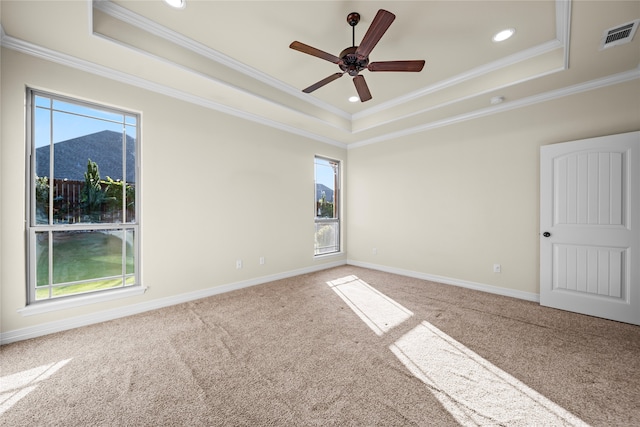 carpeted empty room featuring a mountain view, ceiling fan, crown molding, and a tray ceiling