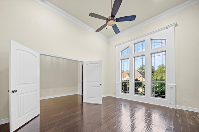 spare room featuring dark wood-type flooring, crown molding, a wealth of natural light, and ceiling fan