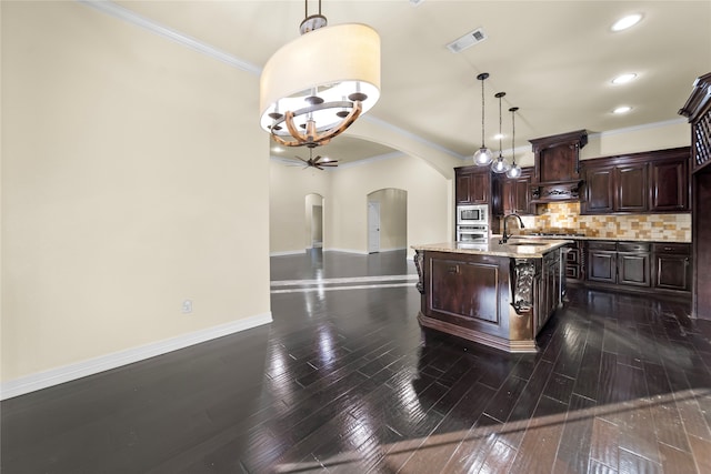 kitchen with tasteful backsplash, dark wood-type flooring, appliances with stainless steel finishes, pendant lighting, and dark brown cabinetry