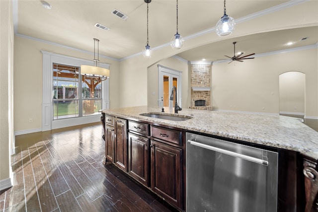 kitchen with hanging light fixtures, dark hardwood / wood-style flooring, sink, dishwasher, and a stone fireplace