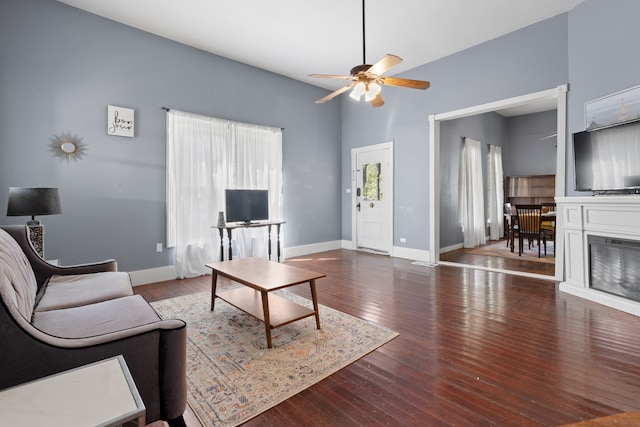 living room with ceiling fan, a towering ceiling, and hardwood / wood-style flooring