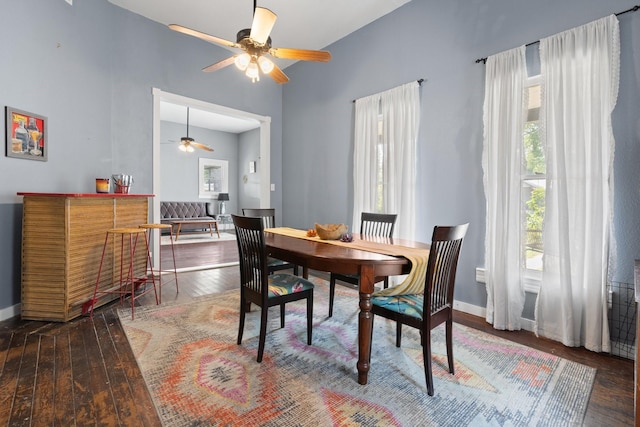 dining space featuring a high ceiling, baseboards, ceiling fan, and hardwood / wood-style floors