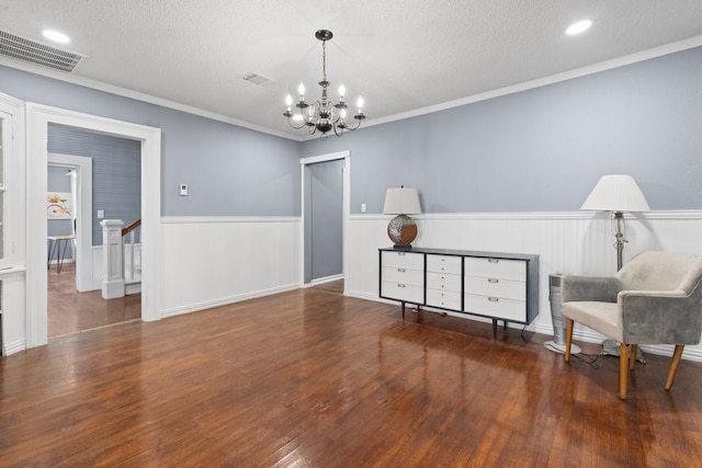 sitting room featuring hardwood / wood-style floors, crown molding, a textured ceiling, and a notable chandelier