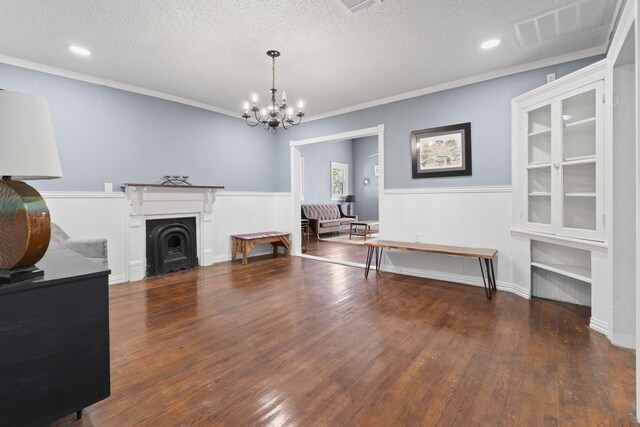 living room with a textured ceiling, ornamental molding, hardwood / wood-style flooring, and a chandelier