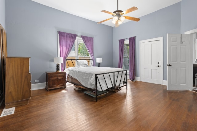 bedroom with ceiling fan, hardwood / wood-style flooring, and a high ceiling