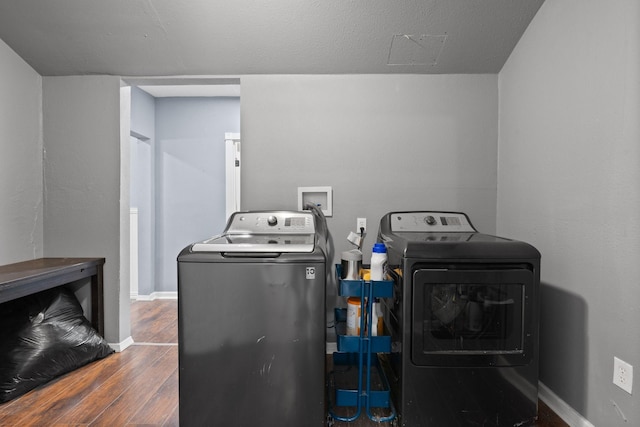 washroom featuring baseboards, wood finished floors, and washing machine and clothes dryer