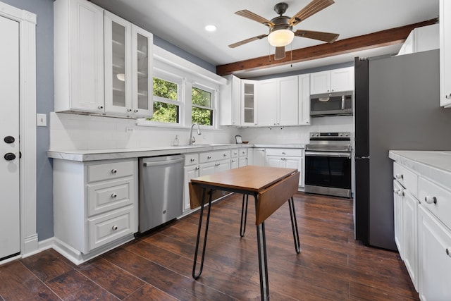 kitchen featuring ceiling fan, white cabinetry, appliances with stainless steel finishes, dark wood-type flooring, and backsplash