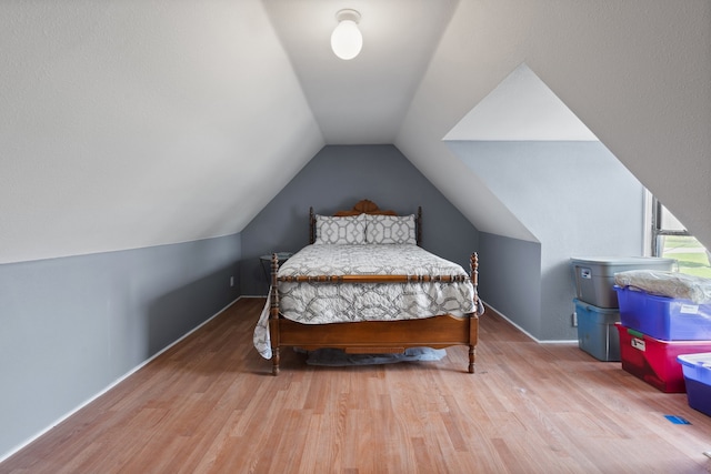 bedroom with wood-type flooring and vaulted ceiling